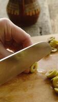Vertical . Slicing vegetables. Cooking process. Female hands are cutting olives on chopping board. video