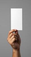 A person holding up a blank card on a gray background photo