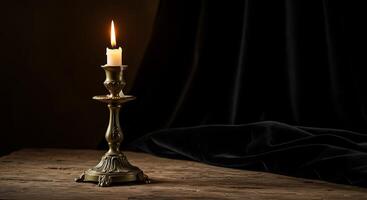 A candle is sitting on a table with a black curtain photo