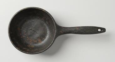 An old cast iron frying pan on a white surface photo