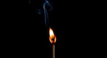 A matchstick is lit on a black background photo