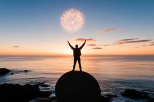 Man standing on rock with fireworks in the background photo