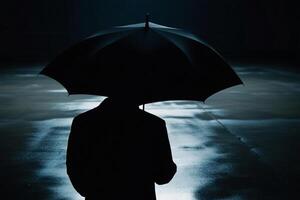 A person standing under an umbrella in the dark photo