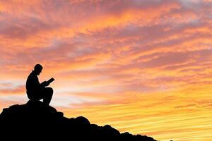Man praying on top of a mountain at sunset photo