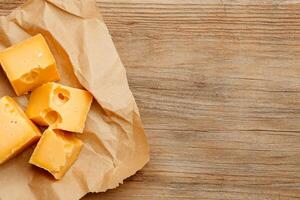 Cheese slices on a brown paper bag on a wooden table photo