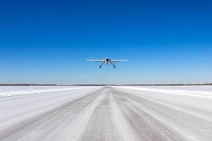 A small plane flying over a snowy road photo