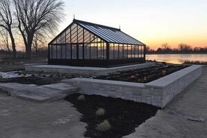 A greenhouse is sitting on the ground next to a lake photo