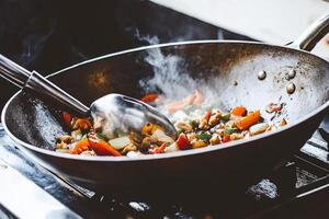 A wok with vegetables cooking on the stove photo