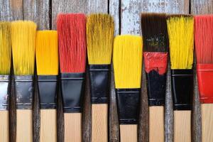 A row of paint brushes on a wooden surface photo