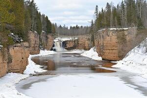 A river flowing through a snowy forest with a bridge photo