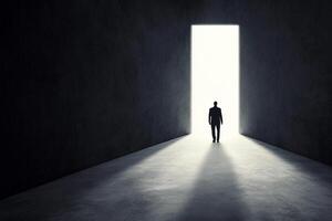 A man standing in an empty room with a light coming from the door photo