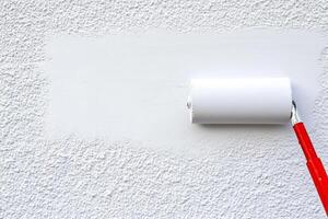 A white wall with a roll of paper and a red paint roller photo