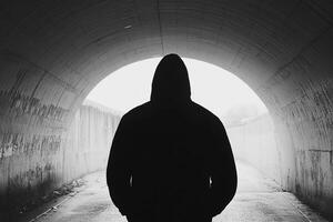A person in a hoodie standing in a tunnel photo