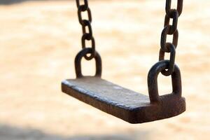 A swing hanging from a chain in a park photo