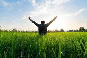 Man in green field with arms up in the air photo