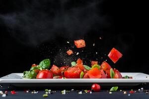 A plate with tomatoes and basil being tossed photo