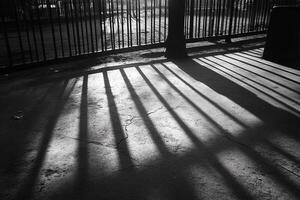 The sun is shining through the shadows of a fence photo