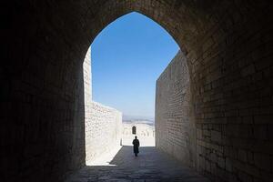 A person walking through an archway in a stone building photo