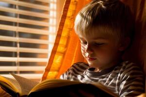A young boy is reading a book in front of a window photo