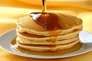 A stack of pancakes on a plate with syrup being poured on top photo