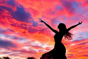 Silhouette of a woman with arms up in the air at sunset photo