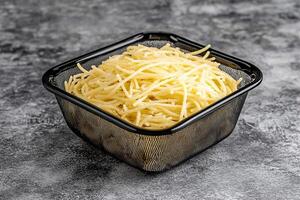 A black square container filled with shredded cheese photo