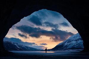 A person standing in front of a cave at sunset photo