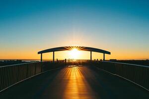 A bridge with a sun setting behind it photo