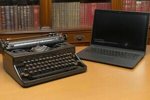 A laptop computer and a typewriter on a desk photo