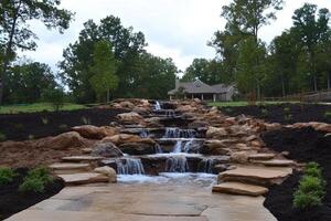 A waterfall in a backyard with rocks and plants photo