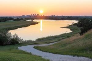 A river runs through a grassy field with a city in the background photo