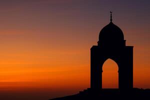 An awe-inspiring image capturing the silhouette of a mosque against the breathtaking backdrop of a vibrant sunset. photo