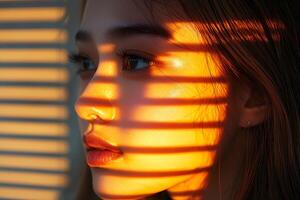 Woman with blinds shadow on face enjoying golden hour light photo