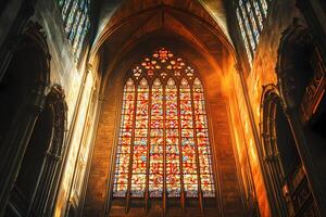 Sunlight shining through colorful stained glass window in gothic cathedral photo