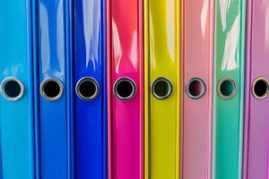 Colorful ring binders standing in a row creating a vibrant rainbow pattern photo