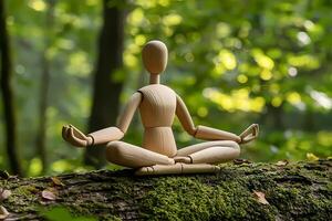 Wooden mannequin meditating in the lotus position on mossy tree trunk in lush forest photo