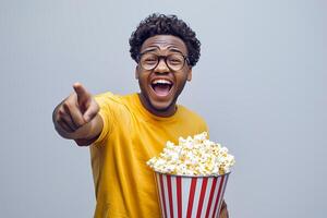 Excited man enjoying movie with popcorn and pointing finger photo