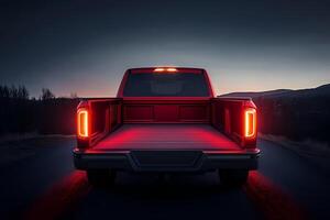 Red pickup truck parked on road at dusk with open trunk and illuminated cargo area photo