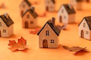 Miniature ceramic houses and autumn leaves creating a cozy fall atmosphere photo