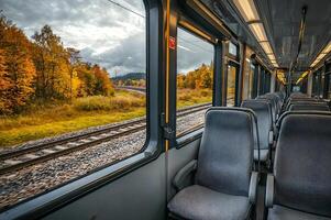 Empty train traveling through autumn landscape with colorful trees and cloudy sky photo