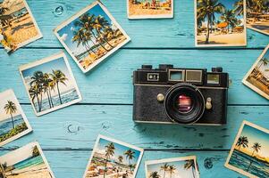 Vintage camera lying on light blue table surrounded by beach photos