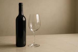 Red Wine Bottle and Empty Glass on Beige Table in Soft Light photo