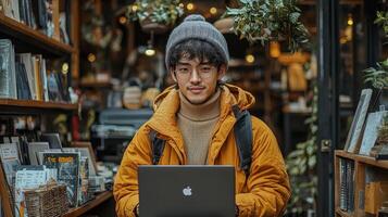 A young man in a yellow jacket holding a laptop photo