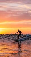 A man riding a surfboard in the ocean at sunset photo