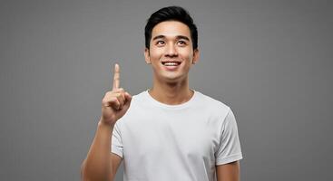 Asian man pointing finger up on gray background photo