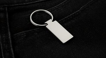 A keychain with a rectangular shape hanging from a black jeans pocket photo