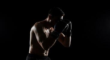 A man in boxing gloves is standing in the dark photo