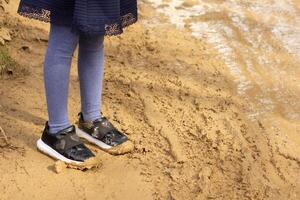 Child legs with shoes in mud outside on dirty roady photo