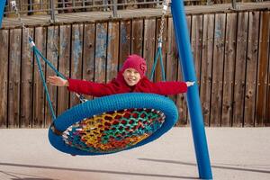 Caucasian smiling childrs swinging on round seesaw looking at camera in motion photo