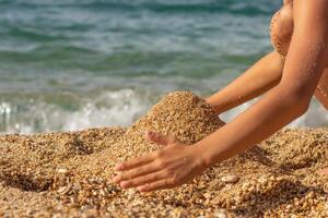 Caucasian child hands building sand castle on sea beach photo